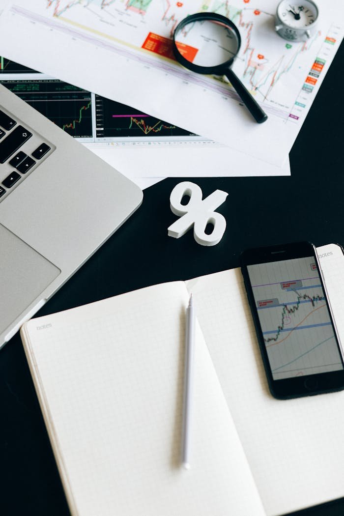 A workspace featuring charts, laptop, smartphone, and a percentage symbol for financial analysis.